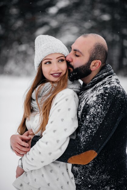 Casal brincando com neve na floresta