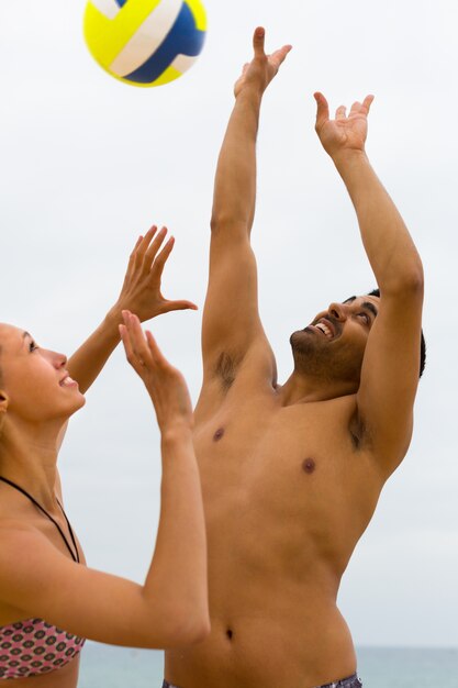 Foto casal brincando com uma bola na praia