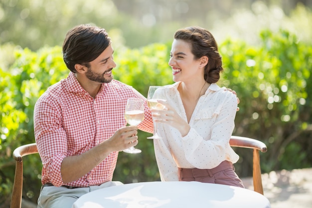 Casal brindando com taças de vinho enquanto está sentado