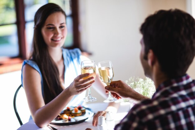 Casal brindando o copo de vinho branco no restaurante