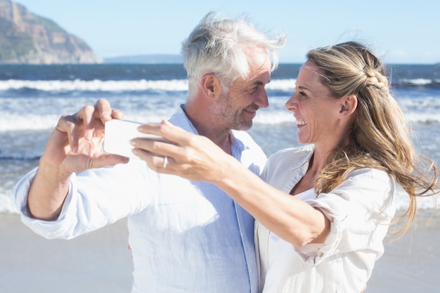 Casal casal na praia juntos tomando um selfie