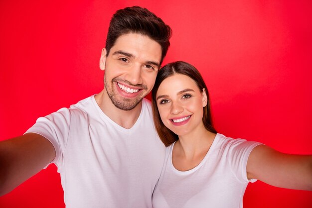 Casal casual posando contra a parede vermelha