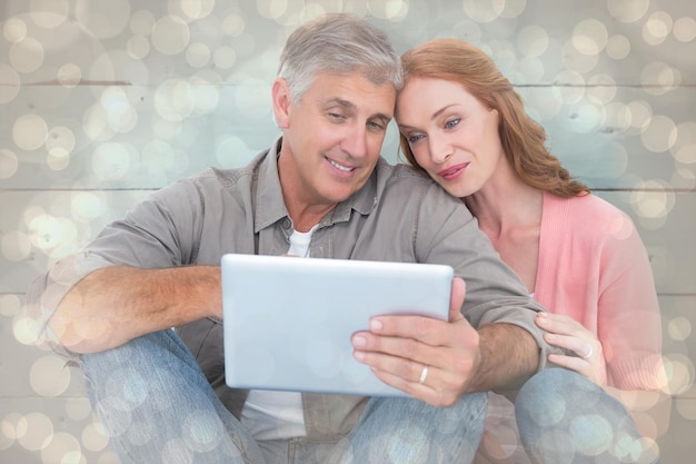 Casal casual sentado usando tablet contra padrão de design de pontos brilhantes de luz