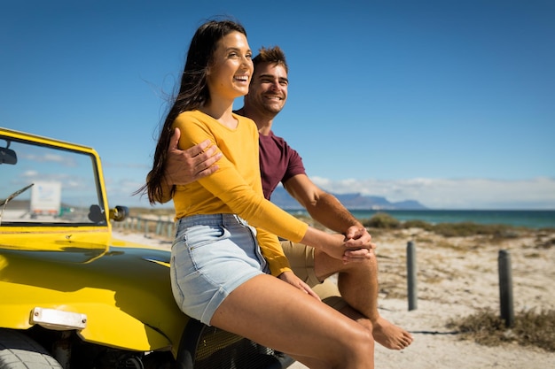 Casal caucasiano feliz sentado no carrinho de praia à beira-mar de mãos dadas. pausa na praia na viagem de férias de verão.