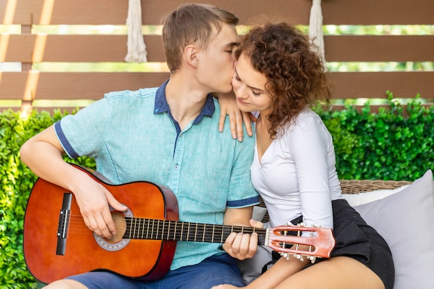 Casal caucasiano tocando violão para sua amada garota.