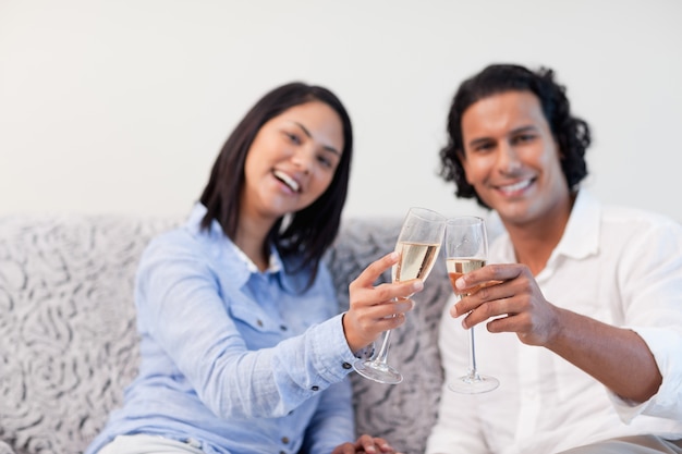 Casal celebrando com vinho espumante no sofá