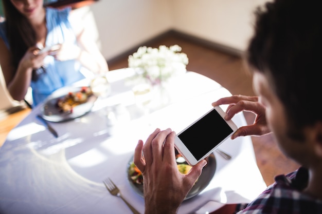 Casal, clicando em foto de um alimento no prato