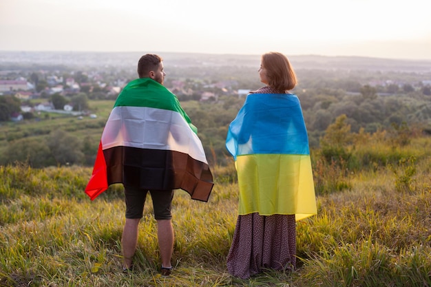 Casal coberto de bandeiras da Ucrânia e dos Emirados Árabes Unidos