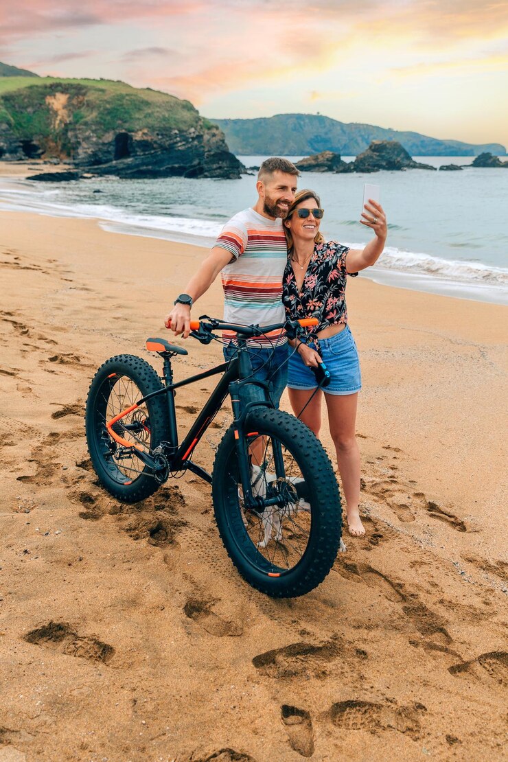 Foto casal com bicicleta gorda tirando uma selfie com o celular na praia