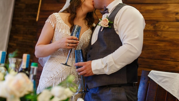 Casal com elegantes taças de vinho decoradas em azul no dia do casamento fecha a porta no fundo