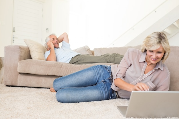 Foto casal com laptop e celular na sala de estar em casa