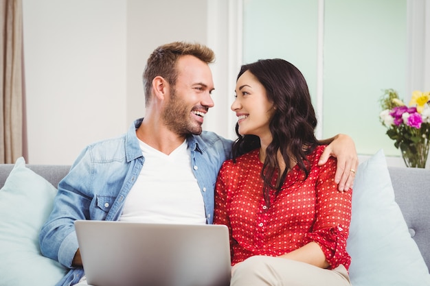 Casal com localização de laptop no sofá em casa