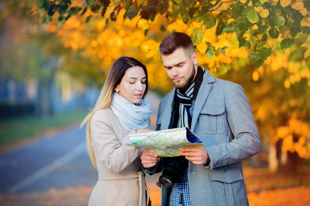 Casal com mapa e câmera no beco da cidade outono.