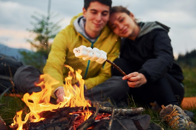 Casal com marshmallow perto da fogueira majestic carpathian mountains bela paisagem de natureza intocada