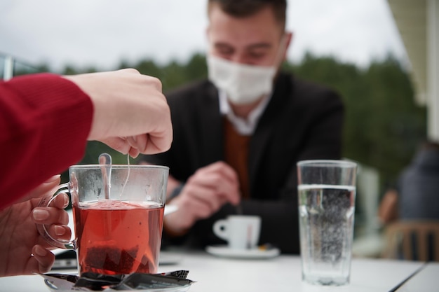 casal com máscara médica protetora tomando café em um restaurante, novo conceito normal de coronavírus
