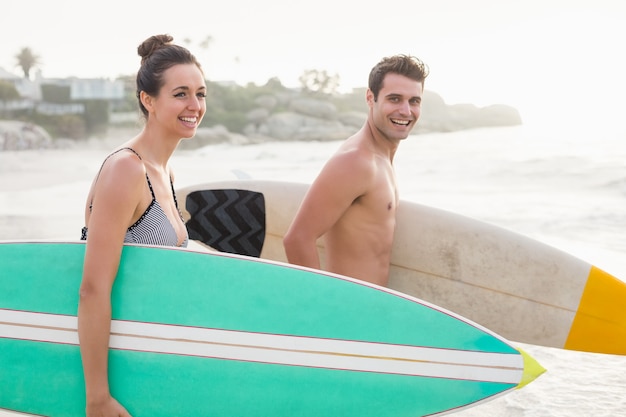 Casal com prancha correndo na praia