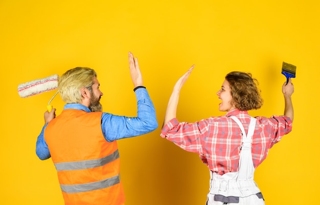 Casal com rolo de pintura. siga as etapas de reparo. vestir uniforme especial e usar ferramentas. serviço de manutenção. conceito de construção. imagine sua nova casa. retrato de faz-tudo e sua colega.