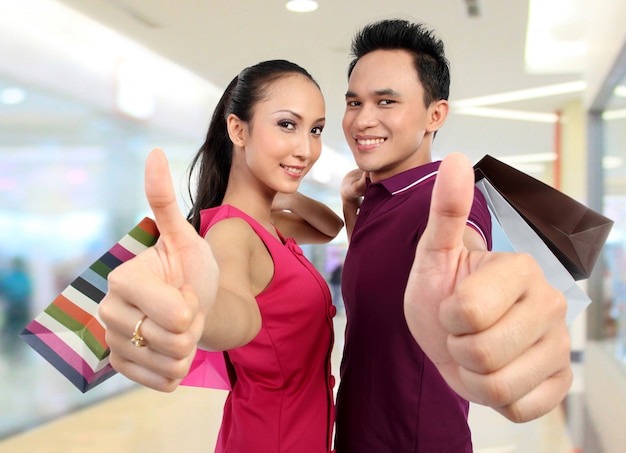 Casal com sacos de compras, aparecendo o polegar