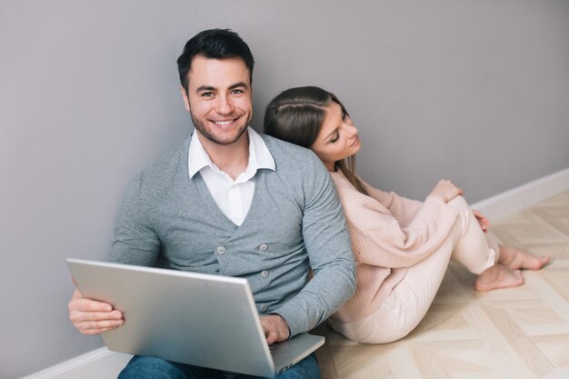 Casal com um laptop sentado no chão. Compras online.