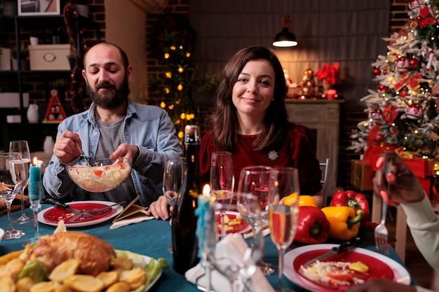 Casal comemorando o natal na festa em casa da família, amigos felizes bebendo vinho espumante na mesa de jantar festiva. esposa e marido comendo pratos de natal cozidos em casa em um lindo lugar decorado