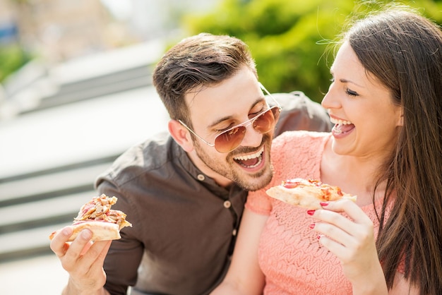 Casal comendo lanche de pizza ao ar livre