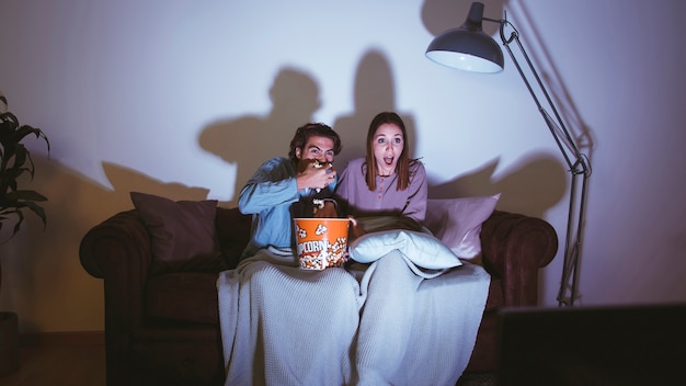 Casal comendo pipoca e tendo uma noite de cinema