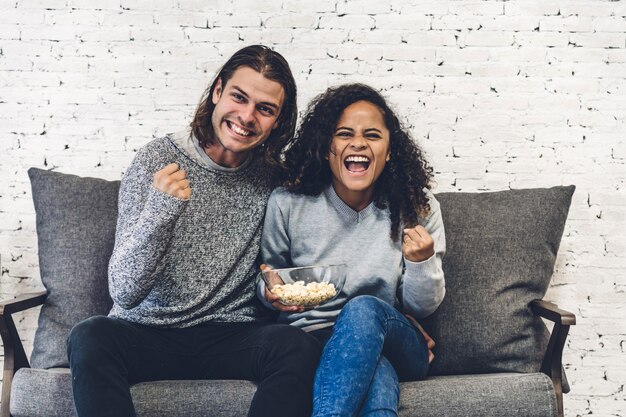 Foto casal comendo pipoca juntos e assistindo tv