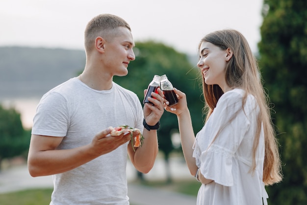 Casal comendo pizza e bebendo na natureza