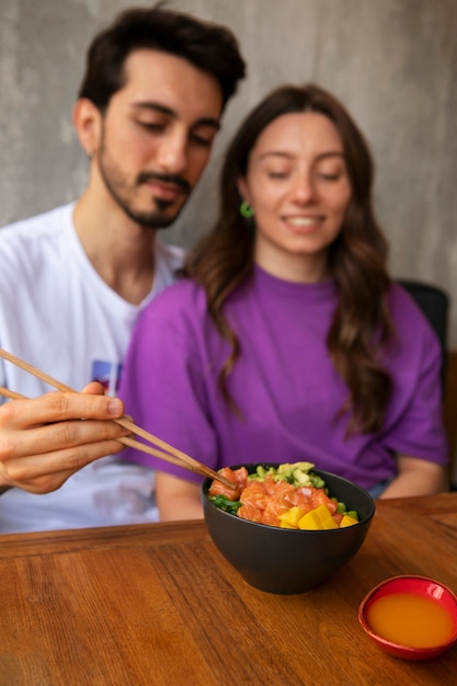 Foto casal comendo tigela de prato de salmão no restaurante
