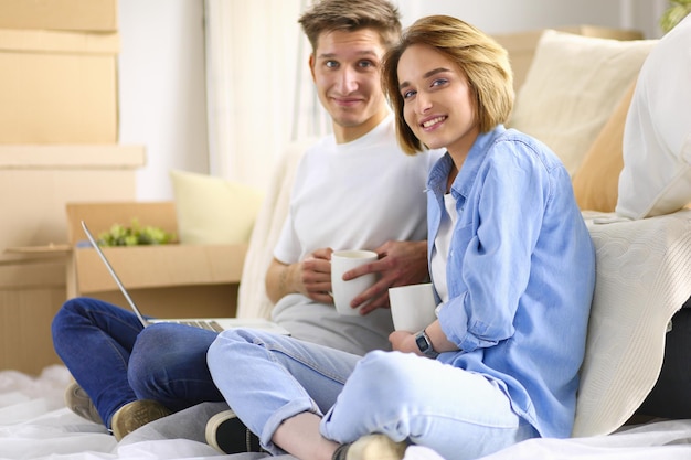 Casal comprando online com um laptop e mudando de casa sentado no chão