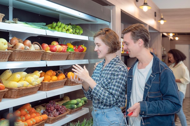 Casal comprando vegetais juntos na prateleira do freezer em loja de conveniência