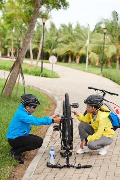 Casal consertando roda de bicicleta