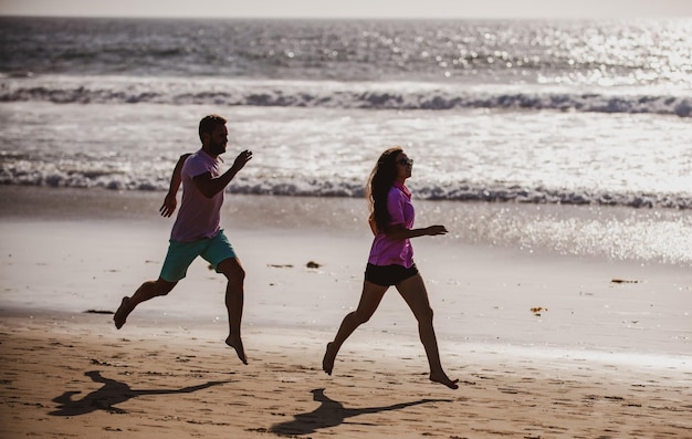 Casal correndo em corredores de esportes de praia correndo na praia malhando o conceito de exercício de fitness ao ar livre