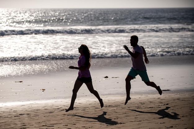 Casal correndo na praia. Corredores de esporte correndo na praia malhando. Conceito de exercício ao ar livre de aptidão.