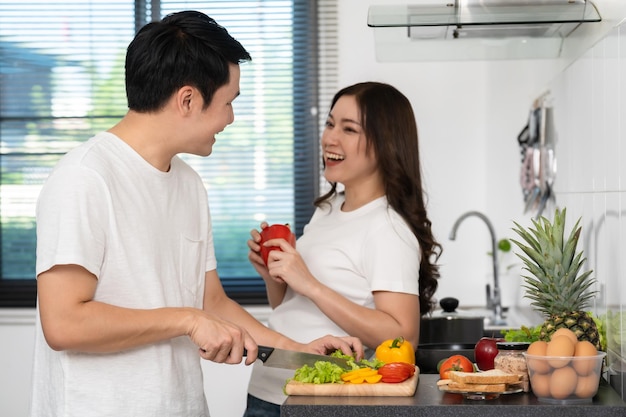 Foto casal cortando legumes para preparar alimentos saudáveis na cozinha em casa