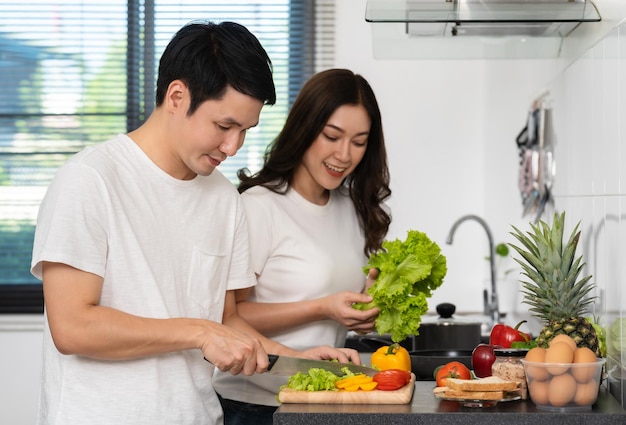 Casal cortando legumes para preparar alimentos saudáveis na cozinha em casa