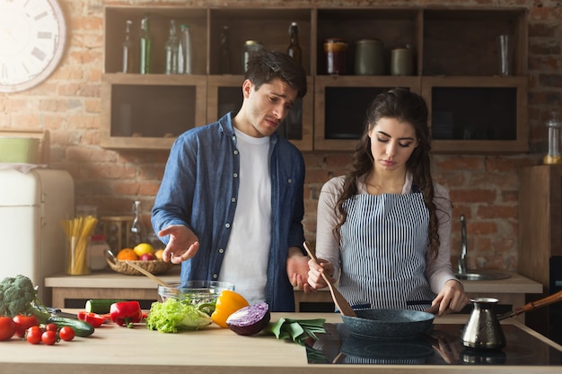 Casal cozinhando um jantar saudável e brigando na cozinha do sótão em casa. Preparando salada de legumes.