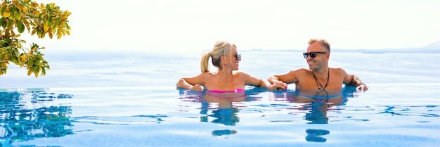 Casal curtindo férias na piscina infinita com bela vista para o mar