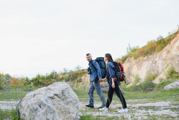 Casal curtindo lindas vistas das montanhas, enquanto viaja com mochilas nas montanhas