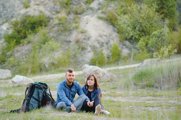 Casal curtindo lindas vistas das montanhas, enquanto viaja com mochilas nas montanhas