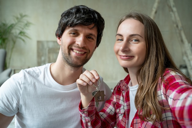 Casal da família mostra orgulhosamente as chaves de sua nova casa