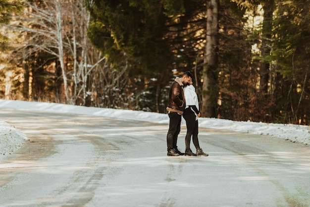 Casal da moda apaixonado se divertindo na natureza do inverno no fundo de uma estrada de neve Foco seletivo