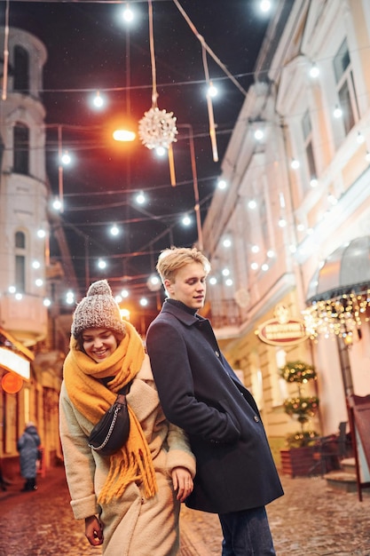 Casal dá um passeio juntos na rua decorada de Natal.