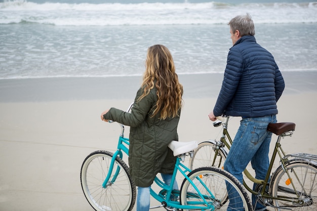 Casal dançando com bicicleta na praia