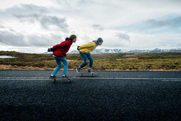 Casal de adolescentes se divertindo patinando e fazendo ladeira abaixo