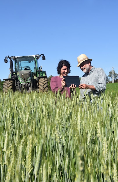 Casal de agricultores em um campo com um tablet digital