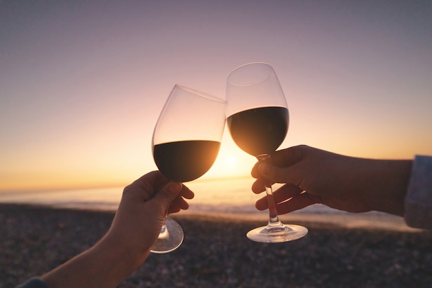 Casal de amantes, bebendo vinho tinto durante assistir o pôr do sol e curtir férias no mar em lua de mel