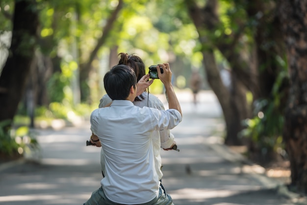 Casal de amantes ciclismo bicicleta por namorada e namorado usar câmera digital tirar uma foto