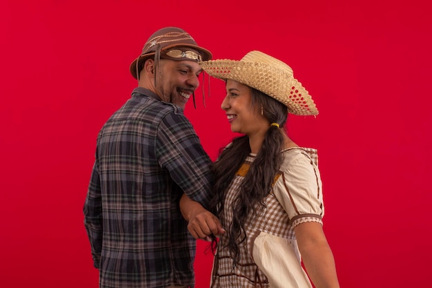 Foto casal de amantes com trajes típicos da festa junina em fotos de estúdio em fundo vermelho brazilian june festival