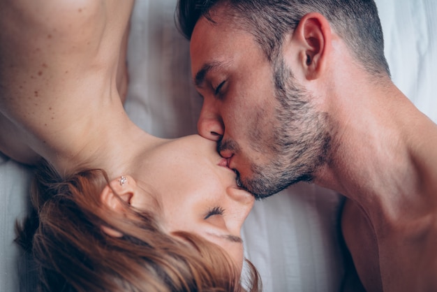 Casal de amantes tendo beijo sexy e romântico em casa na cama de manhã.